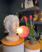 Modern Grace Portable Table Lamp with Pink Glass Globe and White Resin Bust Sculptural Base