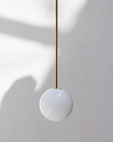 Modern Brass Rod Pendant Light with Spherical Mouth Blown Opal Glass Globe